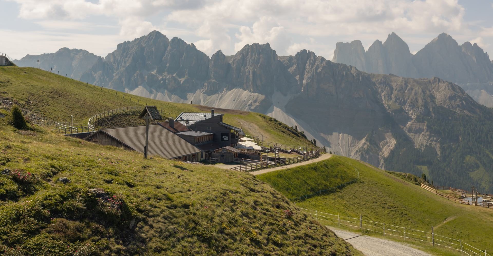 Die Rossalm Plose im Sommer mit Sonnenterrasse vor den Geislerspitzen Die Rossalm Plose im Sommer mit Sonnenterrasse vor den Geislerspitzen